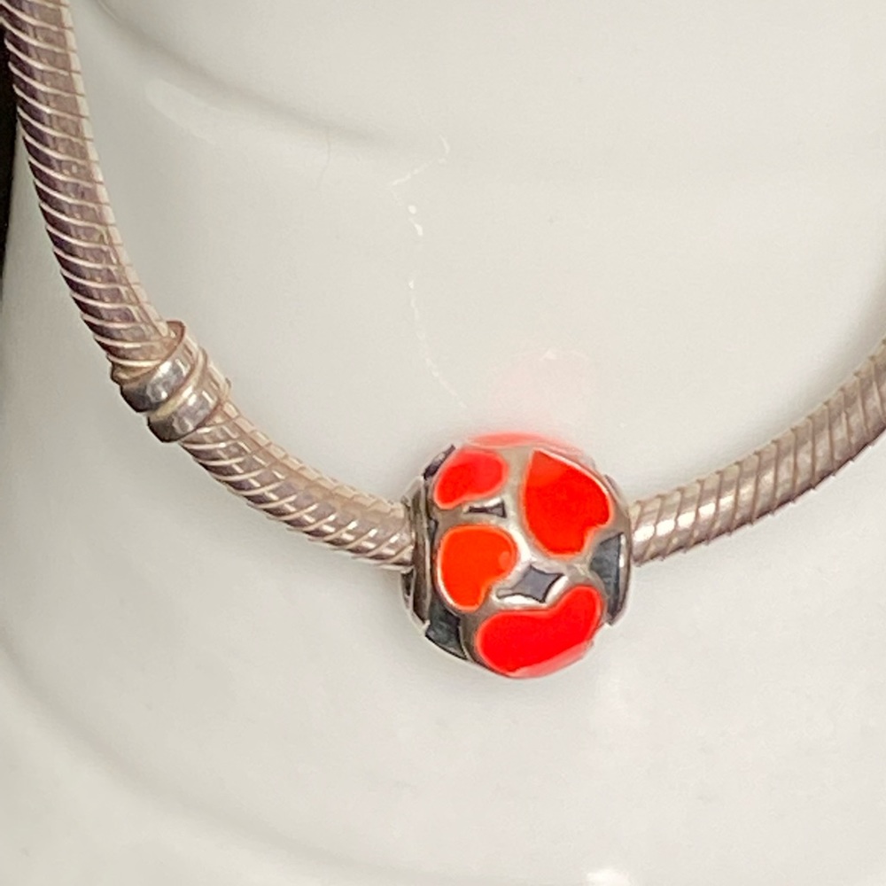 Pandora “love hearts enamel bead charm” in a vivid hot orange and red combo.